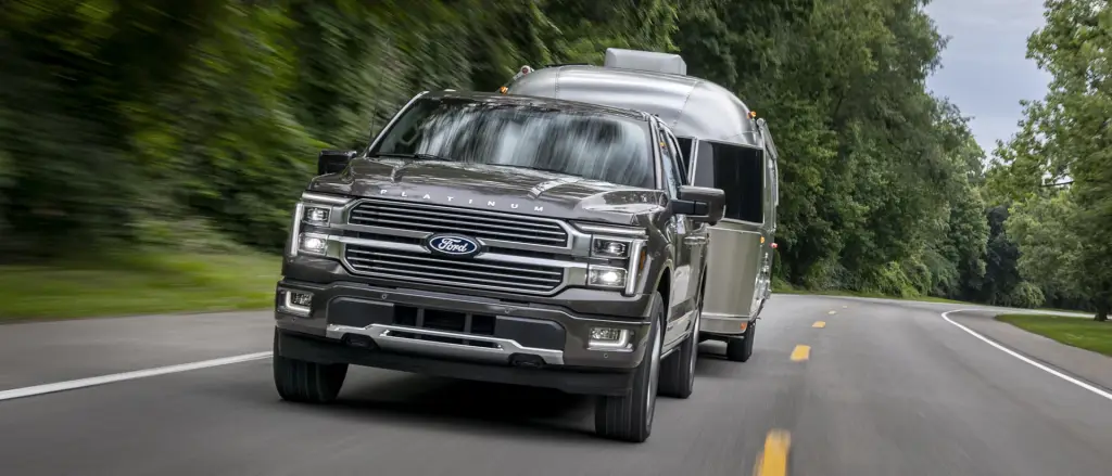 Ford F-150 Platinum towing an Airstream travel trailer on a forested road at Northstar Ford Cars and Trucks